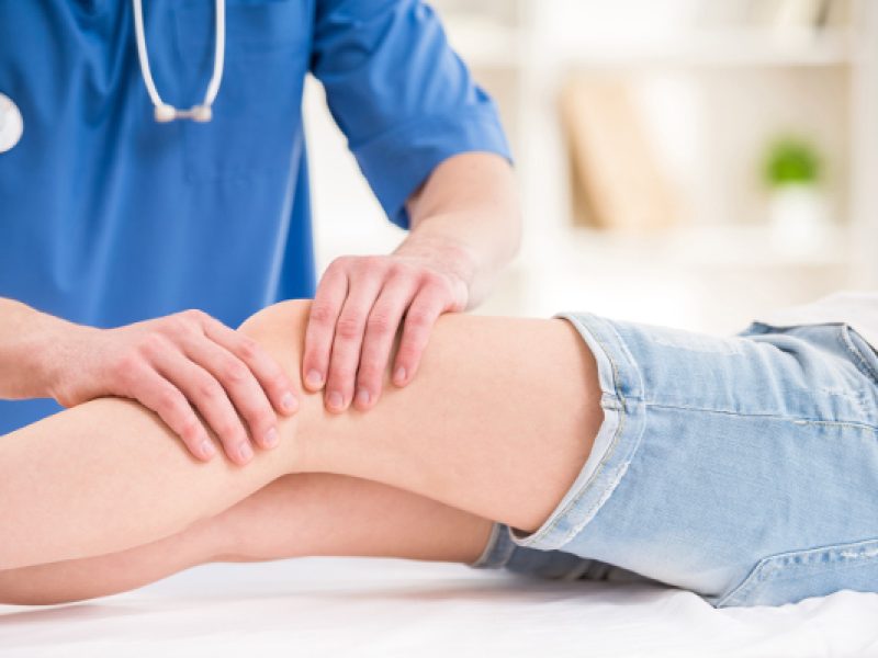 Close-up of male physiotherapist massaging the  leg of female patient in a physio room.